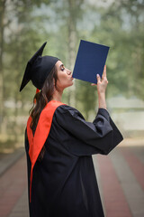 Graduation day. A very happy female student in a master's gown and cap. graduate with a diploma