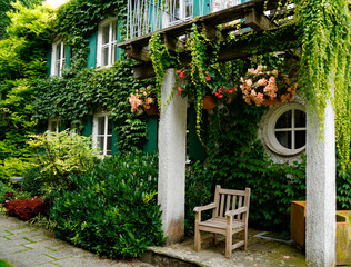 Fototapeta na wymiar romantic house overgrown with ivy and flowers in the botanical garden on a sunny summer day in Augsburg, Bavaria, Germany 