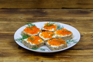 Canapes with red caviar on wooden table
