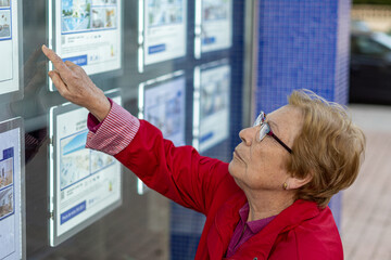 senior woman looking advertisements on the wall of a real state