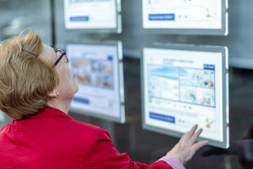 senior woman looking advertisements on the wall of a real state