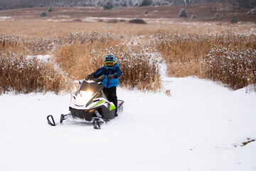 Boy riding snowmobile in the winter time