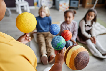 Selective focus on solar system planet models held by teacher standing in front of group of...