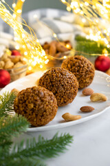 Christmas nut balls cookie on white plate with almond and cashew, Christmas lights bokeh and decor on background. Recipe of dessert for New Year and Christmas holidays menu.