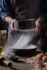 Fototapeta na wymiar Man sifting flour through sieve for bread and bakery ingredients, homemade pasta cooking on table