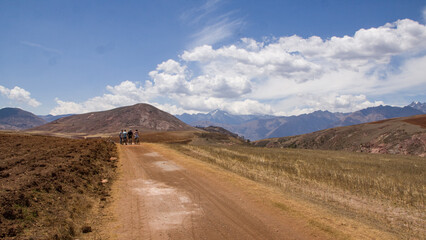 Dry andean landscape with dirt road near mountains and mountain bikers Cusco, Peru