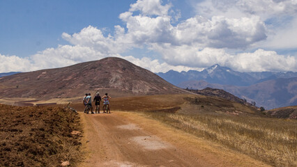 Dry andean landscape with dirt road with bikers at the end near mountains Cusco, Peru