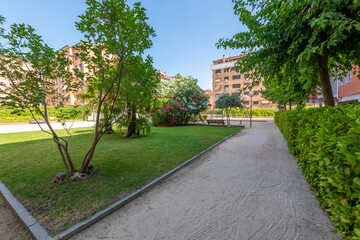 Urban park with views of building facades among trees and gardens with grass and flowers