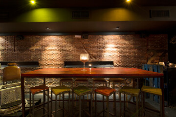High-top restaurant table with wood and metal, lots of matching stools, and exposed brick walls