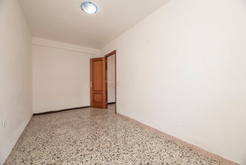 Empty room with polished terrazzo floors and wooden carpentry and sconces with light bulbs on the ceiling
