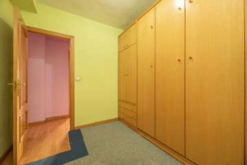 Room with wall covered wooden furniture with pull-down bed and pear-colored cabinets