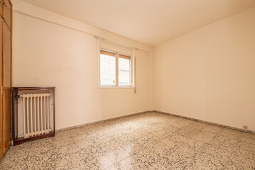 Empty room with built-in wardrobe, white wrought iron radiator and aluminum windows with shutters