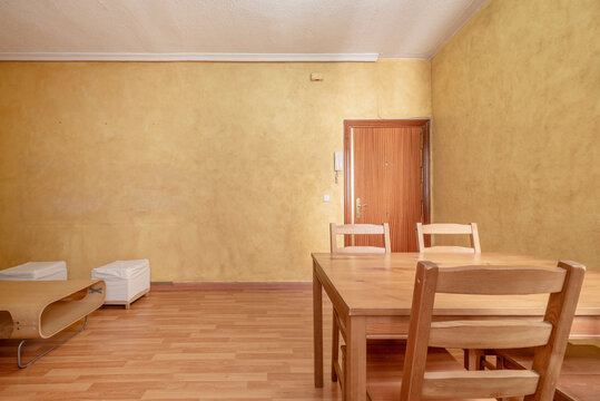 Living room of a house with walls painted in mustard yellow, beech wood furniture and a border on the ceiling