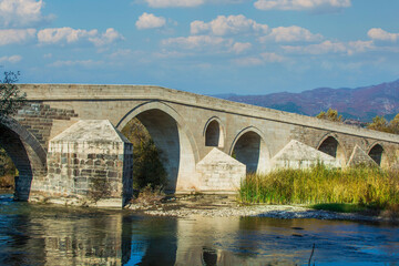 Fototapeta na wymiar Historical Talazan Bridge. It is 15 km from the town of Niksar. Ottoman bridge over Kelkit Stream. Tokat, Turkey 