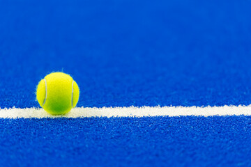 Paddle tennis and tennis ball with white line on blue court.  Horizontal sport poster, greeting cards, headers, website