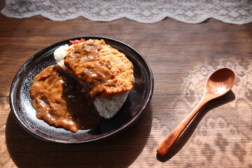 テーブルの上の黒い皿に盛ったカツカレー