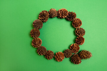 Christmas pine cones wreath on a green background. Flat lay circle frame. 