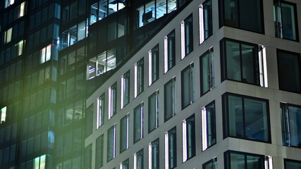 Obraz premium Modern office building in city at the night. View on illuminated offices of a corporate building. Blinking light in window of the multi-storey building of glass and steel. Long exposure at night
