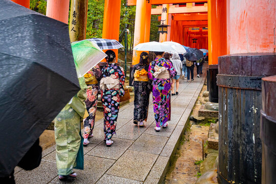 People wearing traditional kimono passing through red gates at Fushimi Inari Taisha