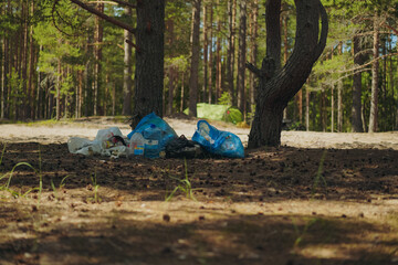Big plastic trash bags left after camping in forest. Environment pollution Garbage collection.