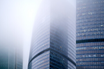 Windows of skyscrapers in the fog, background copy space. Metal structures with windows of a...