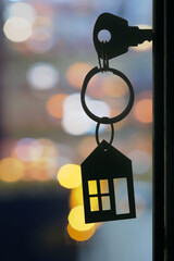 The key with keyring in the door keyhole with blurred night lights background, selective focus