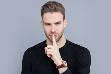 Portrait of man making silence gesture. Handsome man showing shhh with finger near lips