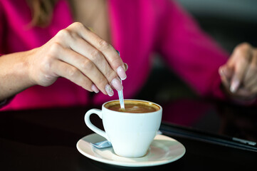 A woman holding coffee spoon and stirring hot coffee