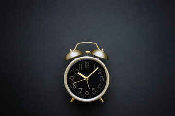 Golden vintage alarm clock on black background. Time concept. Selective focus, copy space