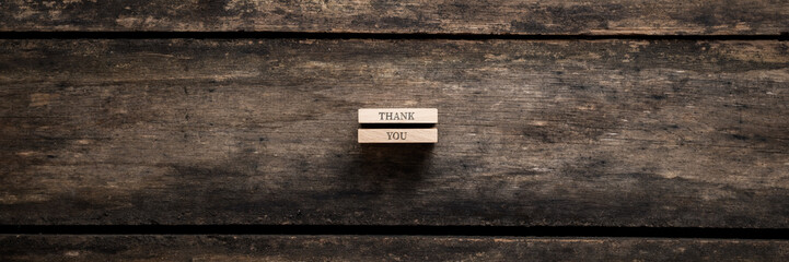 Obraz premium Wide view image of two stacked wooden pegs with a Thank you sign on them