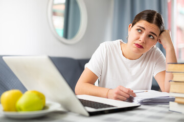 Dissatisfied young woman is tired of online distance learning. Distance learning concept at home