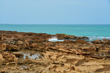 Rocks and waves on a sandy tropical beach.