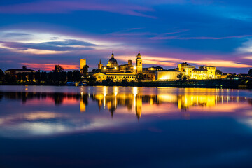 Panoramic evening view of Mantua, Lombardy, Italy; scenic twilight skyline view of the medieval town reflected in the lake waters