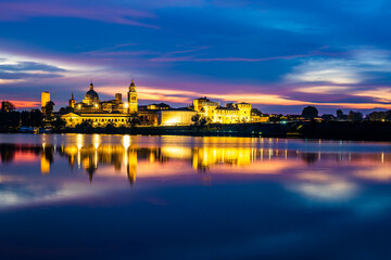 Panoramic evening view of Mantua, Lombardy, Italy; scenic twilight skyline view of the medieval town reflected in the lake waters