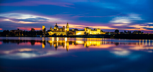 Panoramic evening view of Mantua, Lombardy, Italy; scenic twilight skyline view of the medieval town reflected in the lake waters - Powered by Adobe