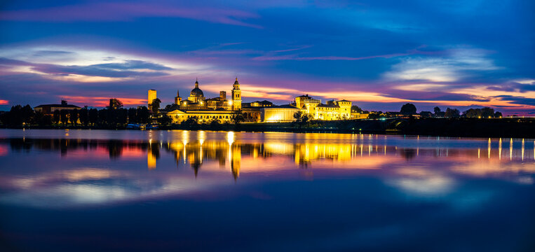 Panoramic evening view of Mantua, Lombardy, Italy; scenic twilight skyline view of the medieval town reflected in the lake waters