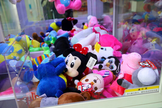 Electronic claw machine to grab stuffed animals. Claw machine. Arcade games room. Video game park for children and teenagers. Peppa Pig,  Minni Mouse, Daisy Duck, Penguin, dino. Disney toys. 