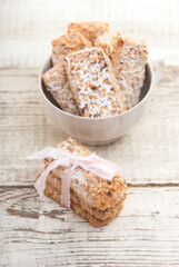 Homemade cookies with nuts and powdered sugar in a cup on a white wooden table.