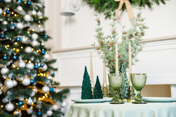 The table is set near the Christmas tree for a romantic New Year's dinner. New Year's festive dinner.