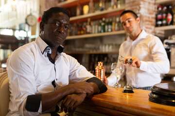 Portrait of adult visitor sitting in the bar while the bartender making a cocktail