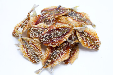 Dried fish with sesame seeds on white background.