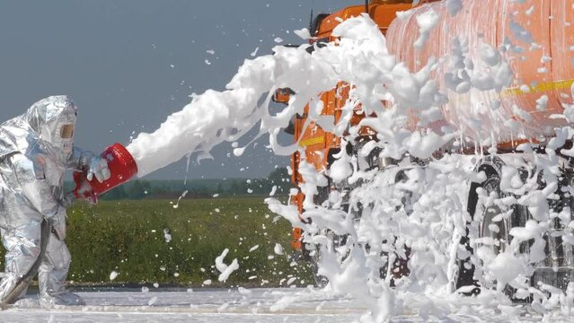 a firefighter in a protective suit pours special foam on a fuel tanker