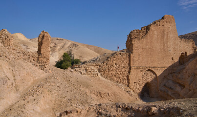 Fototapeta premium Female posing on the remains of aqueduct from the Roman period carrying water to the wadi Qelt valley in Judean Desert near Jericho city. Remains of a beautiful overpass resting on a number of arches.