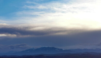 Fototapeta na wymiar Cielo azzurro e nuvole al tramonto sopra i monti le valli e le colline