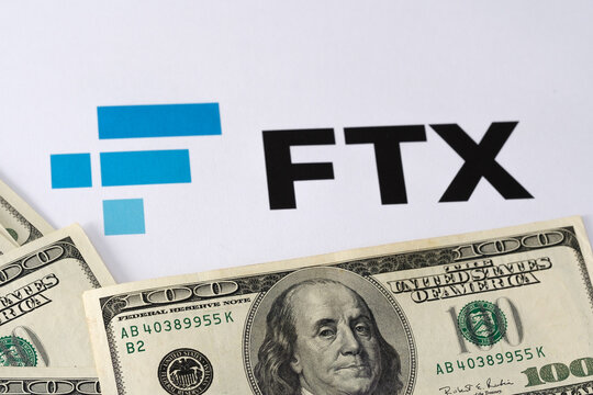 FTX Cryptocurrency Exchange logo printed on paper and US dollars banknotes around it. Concept for company bankruptcy and debt. Stafford, United Kindom, November 22, 2022.
