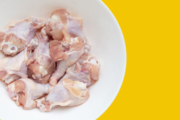 Fresh raw chicken wings (wingstick) in white plate on yellow background.