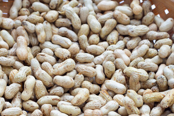 Raw peanuts in bamboo basket on white background.
