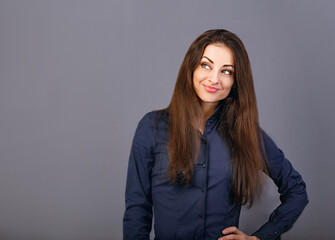 Fototapeta premium Beautiful confident thinking smiling business woman in blue shirt on grey background with empty copy space for text. Closeup