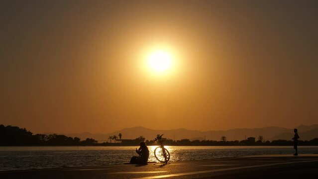 Unrecognizable silhouettes on night seashore. A view of unrecognizable children and males silhouettes pas their time by the sea during sunset.