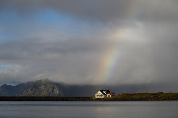 Rainbow emerges from clouds over a sunlit white house
